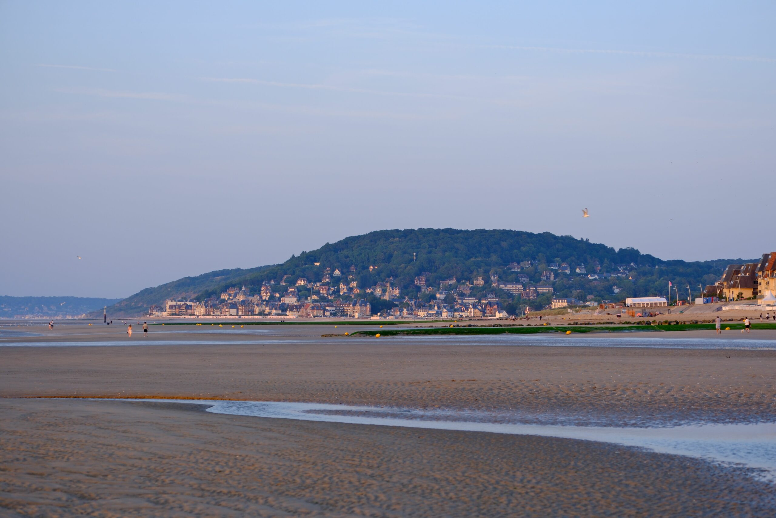 A picturesque view of Cabourg beach, Normandy, with hills in the background at dusk.